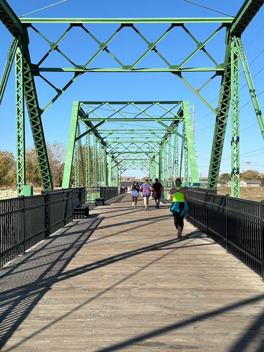 Runners on a green iron bridge