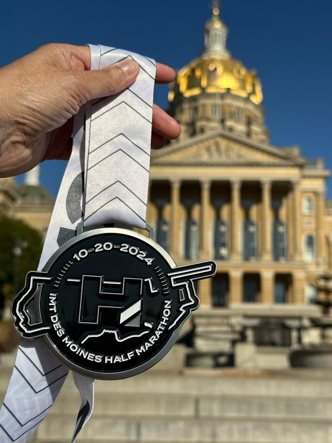 2024 Des Moines half marathon medal against the capitol building
