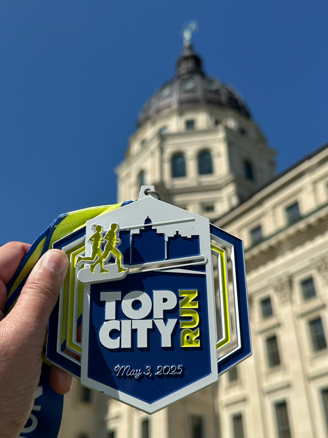 2025 TopCity Half Marathon medal against the capitol building