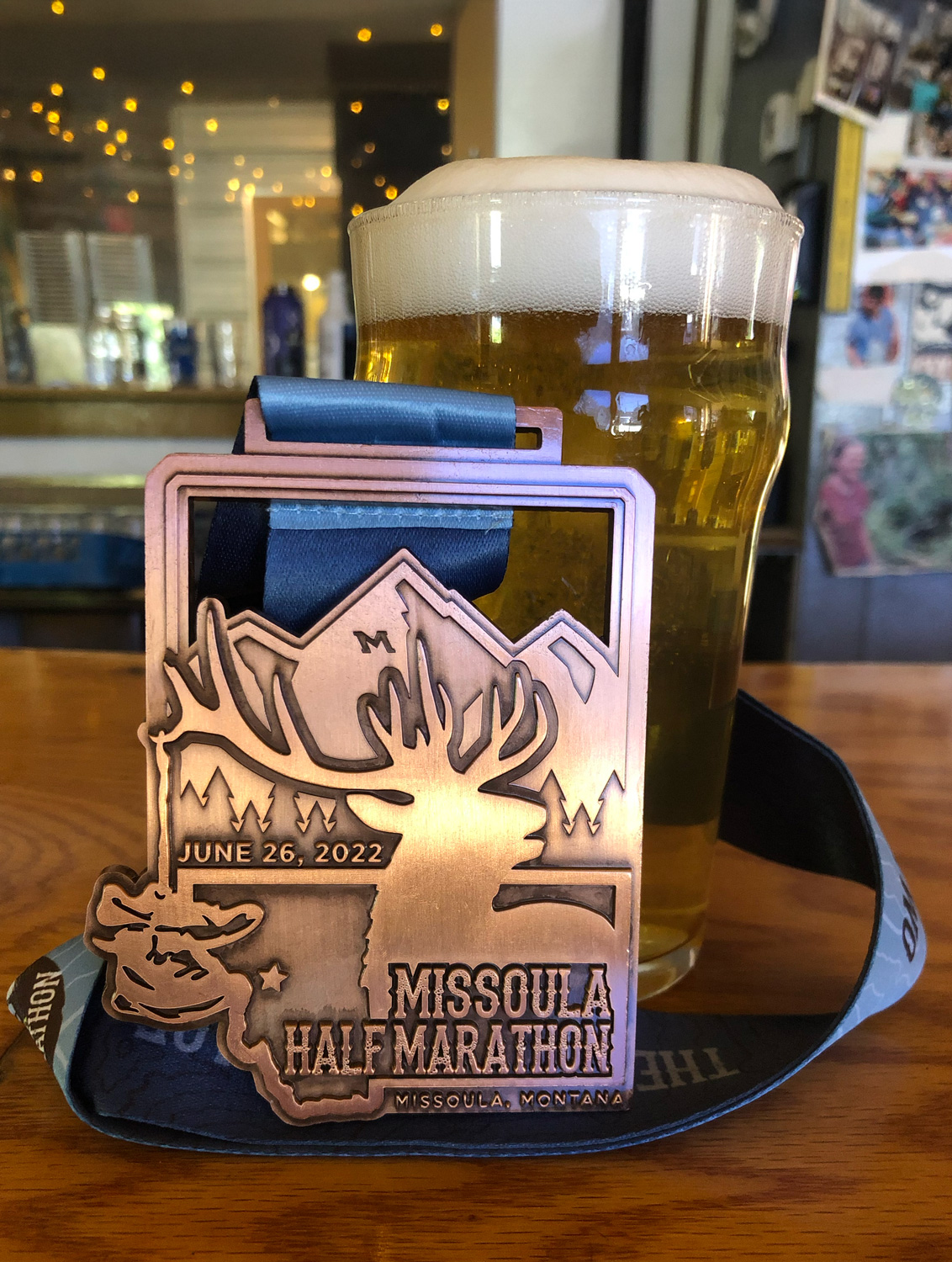 2022 Missoula half marathon medal against a pint glass of beer