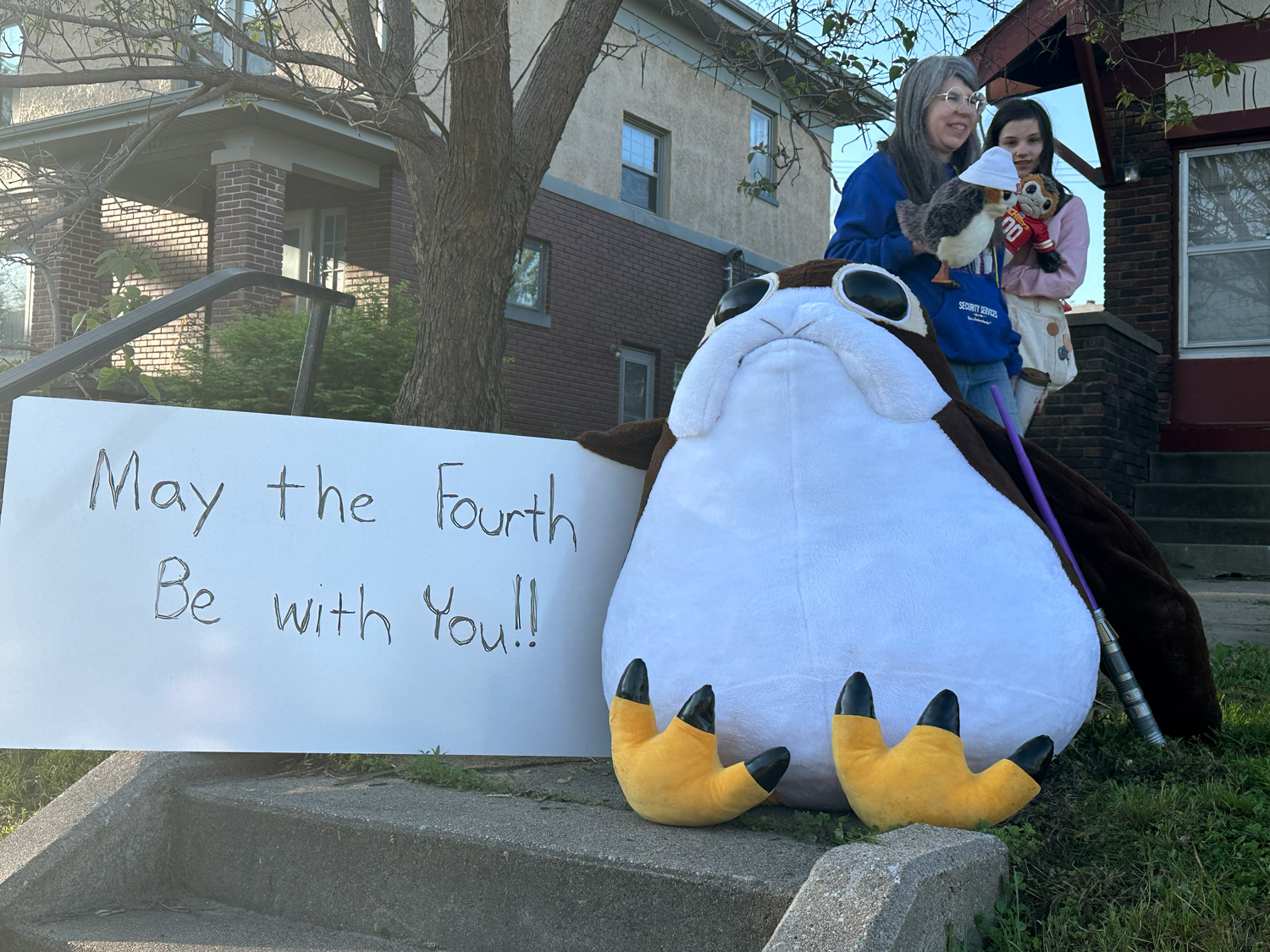 Giant porg plushie by a Star Wars themed sign reading May the Fourth Be With You