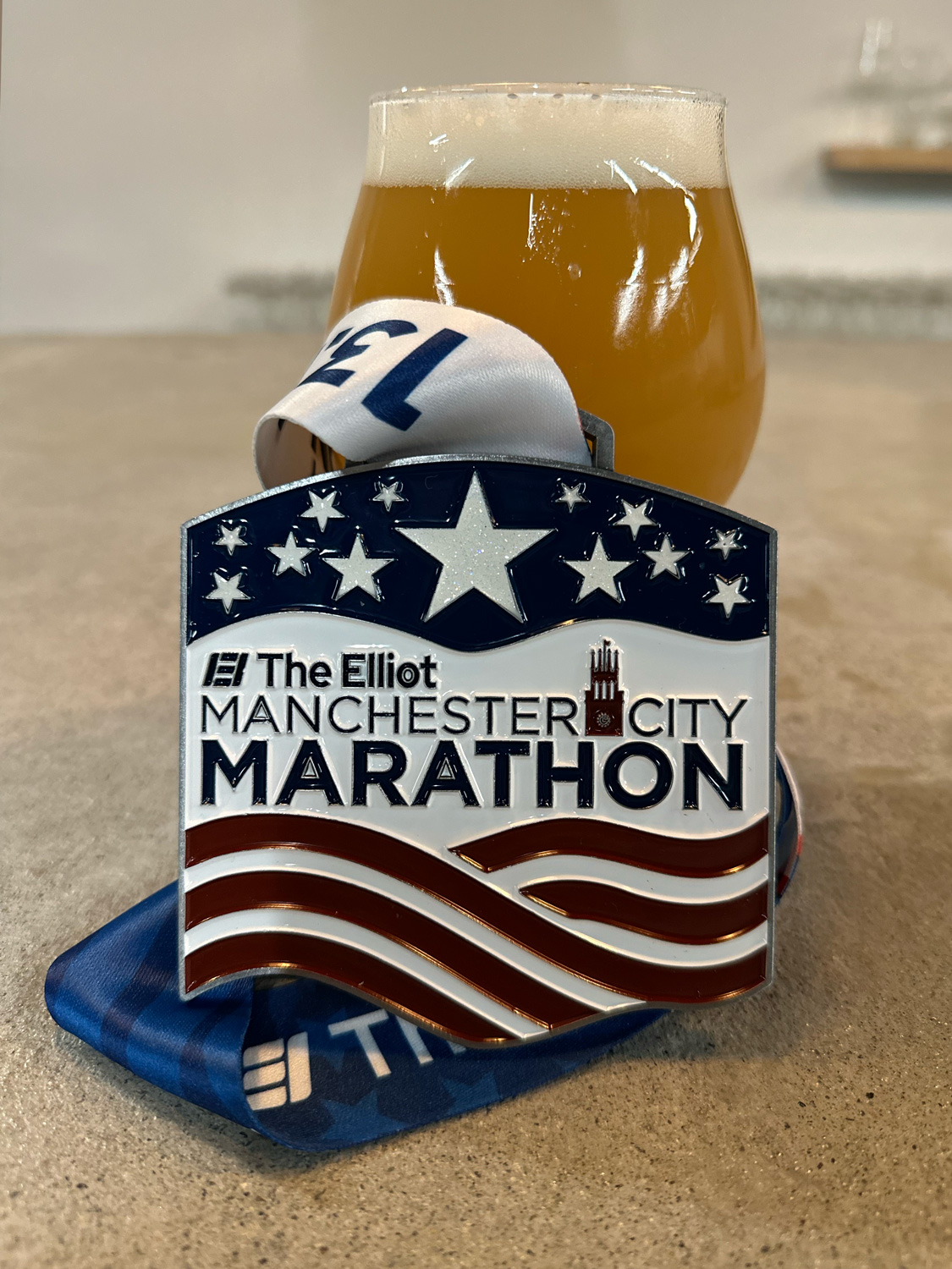 2025 Manchester City Half Marathon medal against a tulip glass of beer