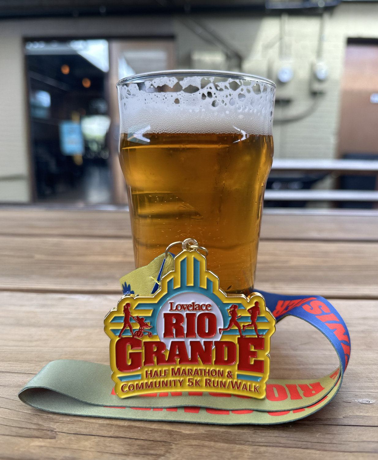 2024 Rio Grande Half Marathon medal against a pint glass of beer