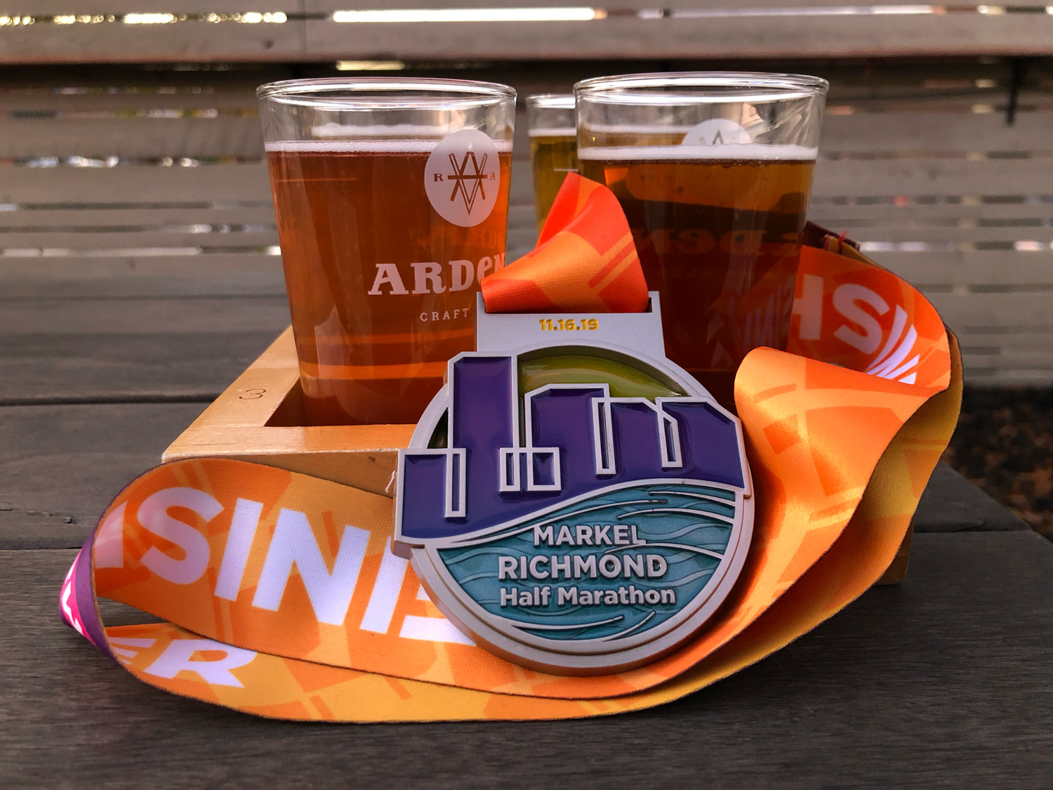 2019 Richmond Half Marathon medal against a flight of 4 beers